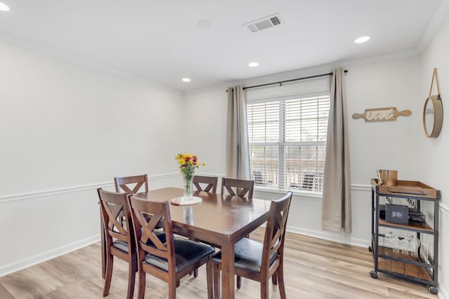 dining space with crown molding, baseboards, visible vents, and light wood-style floors