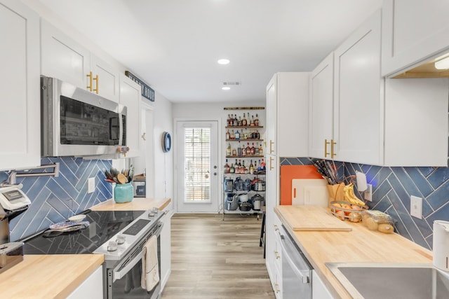 kitchen featuring backsplash, a sink, white cabinets, wood counters, and stainless steel appliances