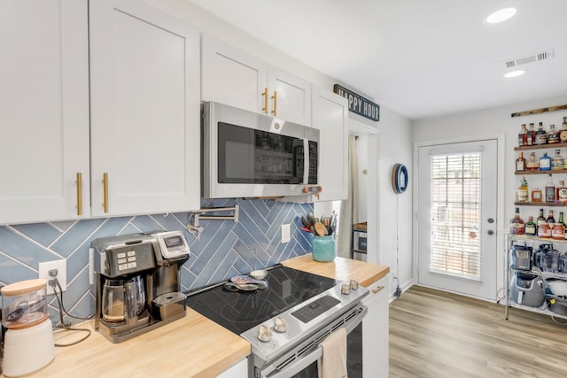 kitchen featuring visible vents, wooden counters, white cabinets, appliances with stainless steel finishes, and backsplash