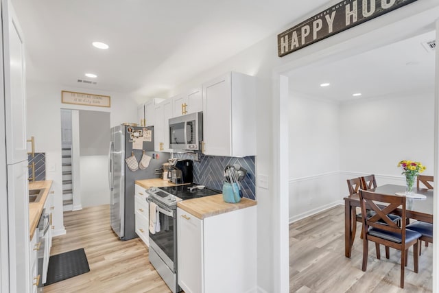 kitchen featuring light wood-style floors, wood counters, stainless steel appliances, tasteful backsplash, and visible vents