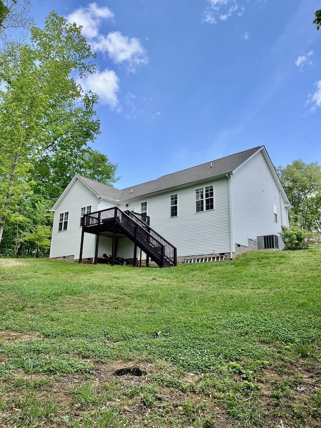 rear view of property featuring a lawn, crawl space, stairway, and a deck