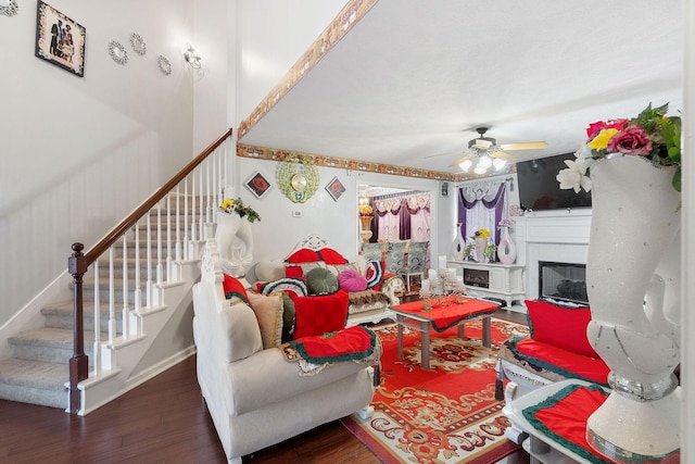 living area featuring a ceiling fan, wood finished floors, and stairway