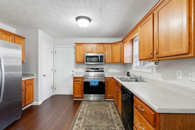 kitchen featuring brown cabinets, a sink, light countertops, stainless steel appliances, and dark wood-type flooring