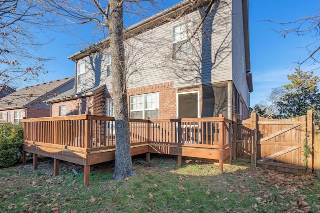 back of house with fence, a gate, a deck, and brick siding