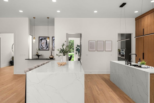 6120 Bresslyn Rd, Nashville, TN 37205 - kitchen with modern cabinets, an island with sink, brown cabinetry, light wood finished floors, and recessed lighting