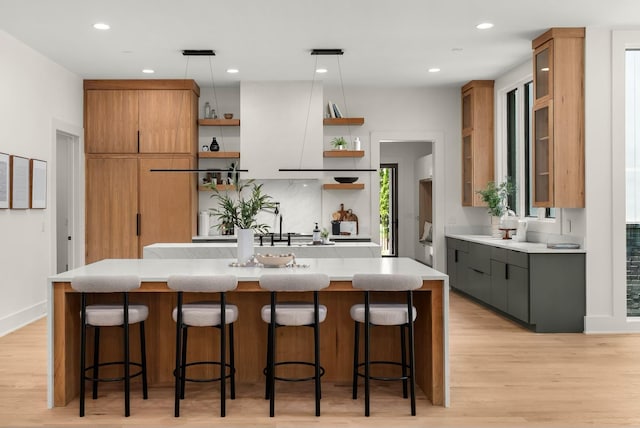 6120 Bresslyn Rd, Nashville, TN 37205 - kitchen featuring open shelves, light countertops, an island with sink, light wood-style flooring, and pendant lighting