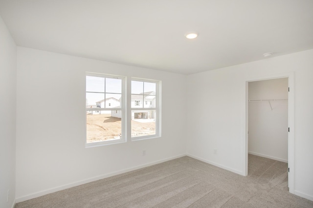 unfurnished bedroom featuring carpet flooring, baseboards, a walk in closet, and a closet