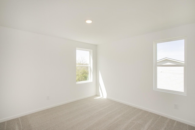 empty room with baseboards, recessed lighting, and light colored carpet