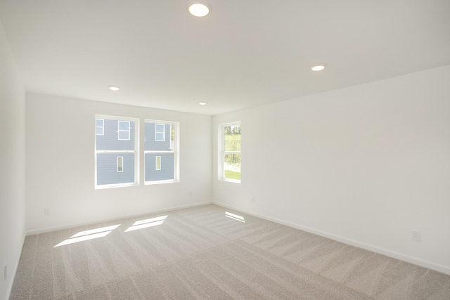 spare room featuring light colored carpet, recessed lighting, and baseboards