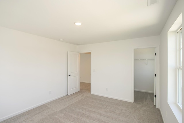 unfurnished bedroom featuring baseboards, visible vents, light carpet, and a spacious closet