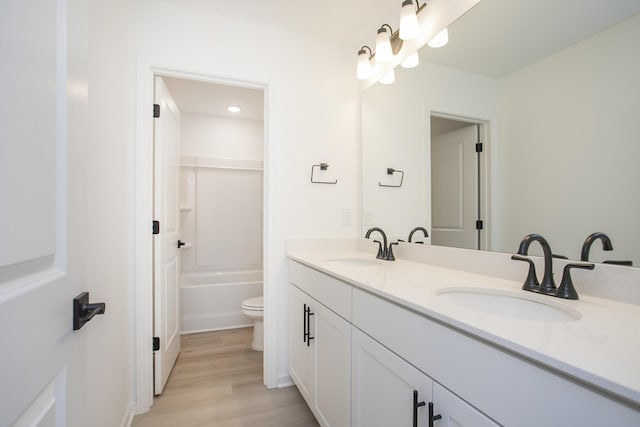 bathroom with a sink, toilet, double vanity, and wood finished floors