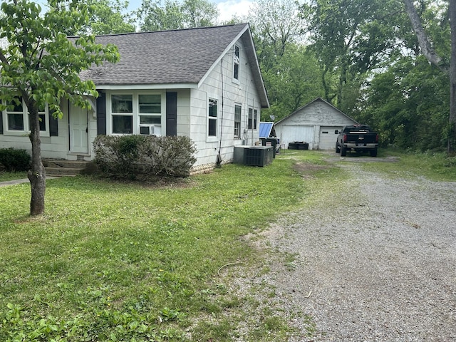 view of side of home with a shingled roof, a garage, an outdoor structure, a yard, and driveway