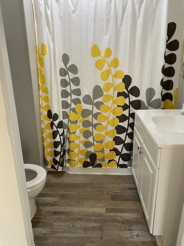bathroom featuring toilet, a shower with curtain, wood finished floors, and vanity