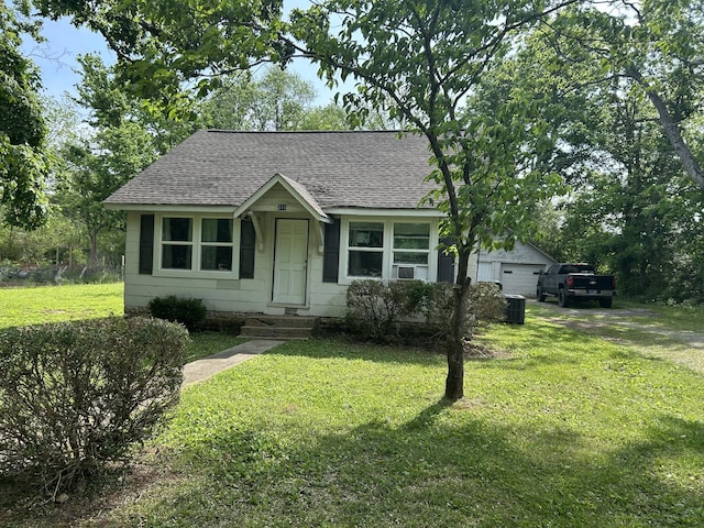 view of front of property with a front lawn, roof with shingles, and cooling unit