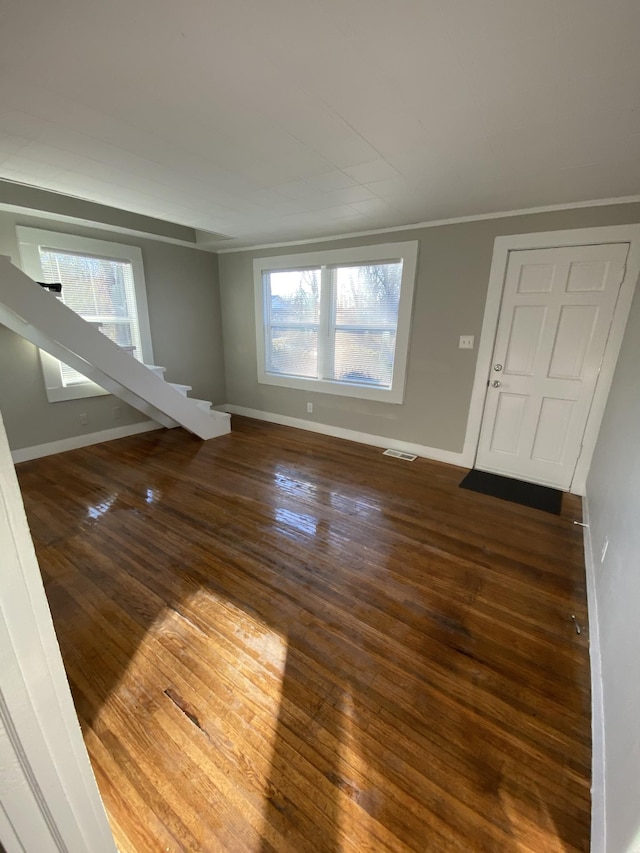 empty room featuring baseboards, dark wood finished floors, plenty of natural light, and visible vents