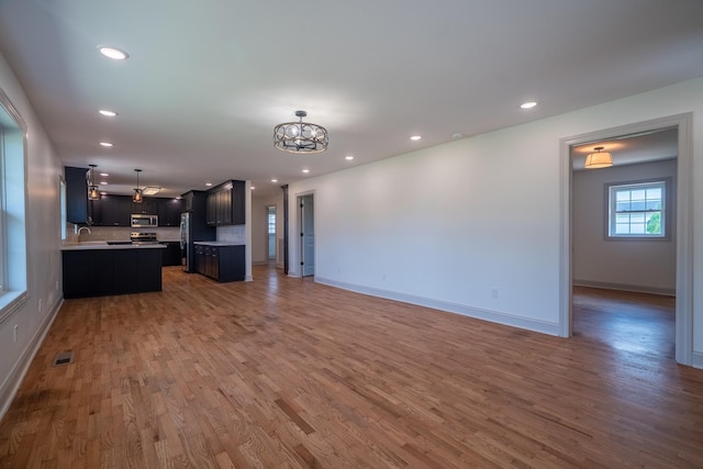 unfurnished living room featuring visible vents, wood finished floors, baseboards, a chandelier, and recessed lighting