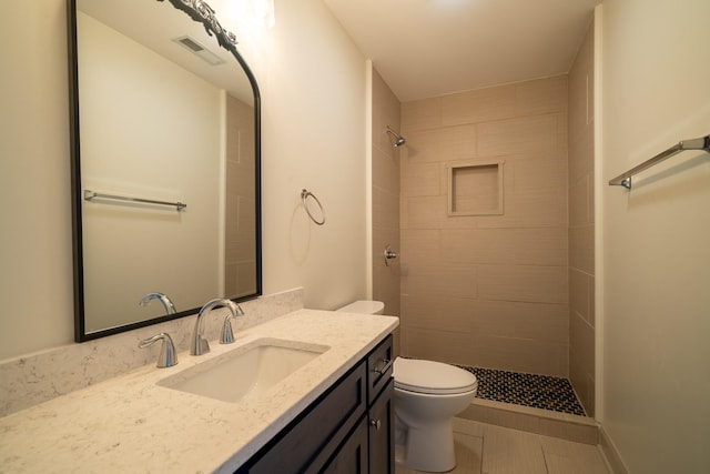full bathroom featuring visible vents, a tile shower, vanity, tile patterned floors, and toilet