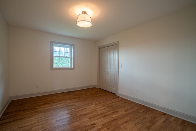 spare room with baseboards, wood finished floors, and visible vents