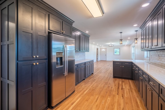 kitchen with stainless steel fridge, light wood finished floors, a peninsula, recessed lighting, and decorative backsplash