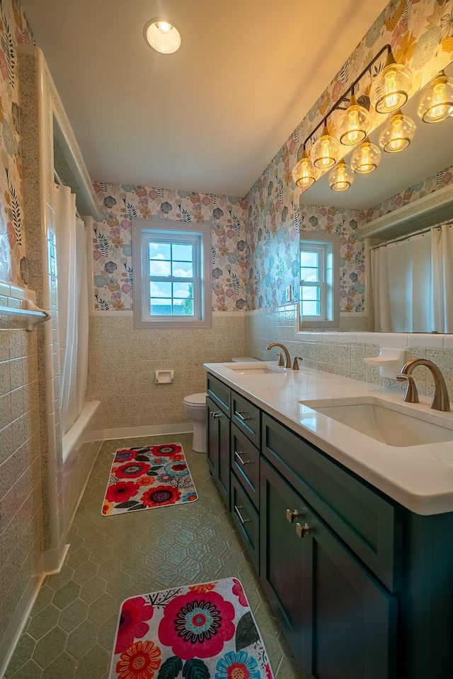 bathroom featuring tile patterned floors, plenty of natural light, a sink, and wallpapered walls