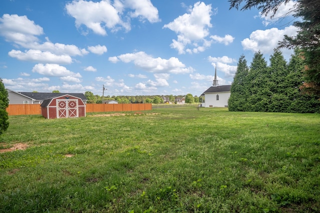 view of yard featuring a storage shed, fence, and an outbuilding