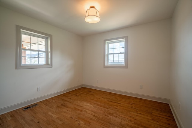 unfurnished room featuring visible vents, baseboards, and wood finished floors