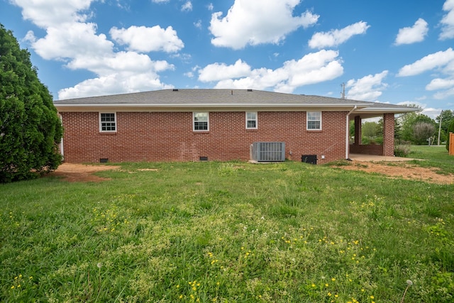 rear view of property featuring central AC, brick siding, crawl space, a yard, and a carport