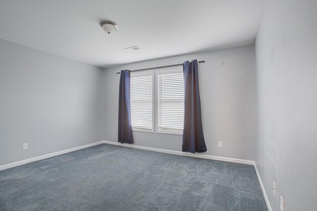 spare room with dark carpet, baseboards, and visible vents
