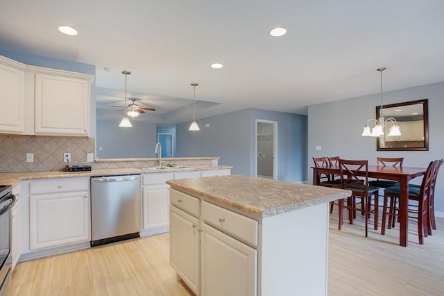 kitchen featuring backsplash, stainless steel dishwasher, ceiling fan with notable chandelier, a peninsula, and light wood-style floors