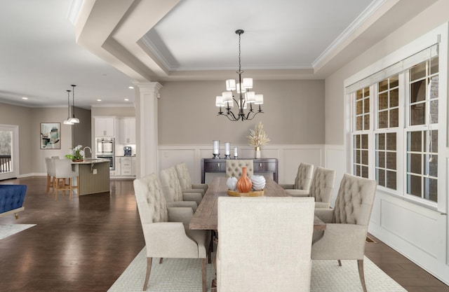 dining room with crown molding, wainscoting, decorative columns, dark wood-style floors, and a raised ceiling