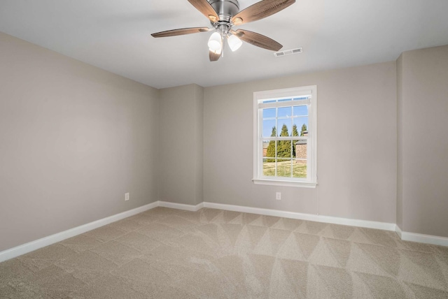 empty room with baseboards, visible vents, light carpet, and ceiling fan