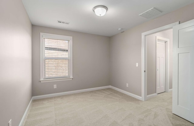 spare room featuring visible vents, baseboards, and light carpet