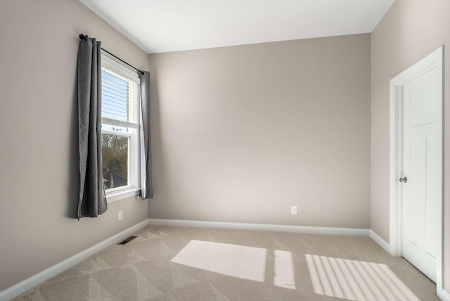 empty room featuring baseboards, light colored carpet, and visible vents