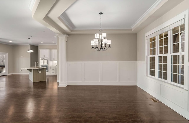 unfurnished dining area with wainscoting, ornate columns, dark wood-style floors, and ornamental molding