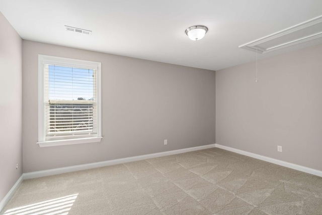 spare room featuring baseboards, attic access, light colored carpet, and visible vents