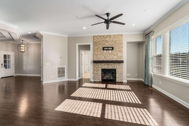 unfurnished living room featuring crown molding, a stone fireplace, ceiling fan with notable chandelier, and hardwood / wood-style floors