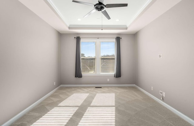 unfurnished room featuring a ceiling fan, baseboards, light colored carpet, and a raised ceiling