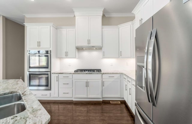 kitchen with crown molding, light stone countertops, appliances with stainless steel finishes, dark wood finished floors, and white cabinetry