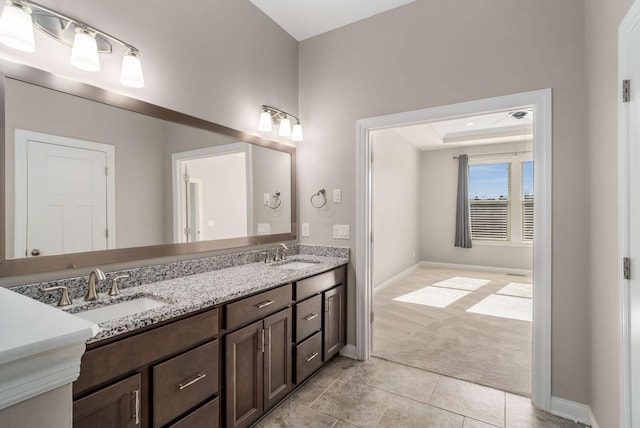 bathroom with a sink, baseboards, tile patterned flooring, and double vanity