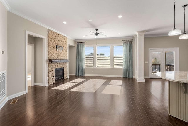unfurnished living room featuring a healthy amount of sunlight, ceiling fan, decorative columns, and a stone fireplace