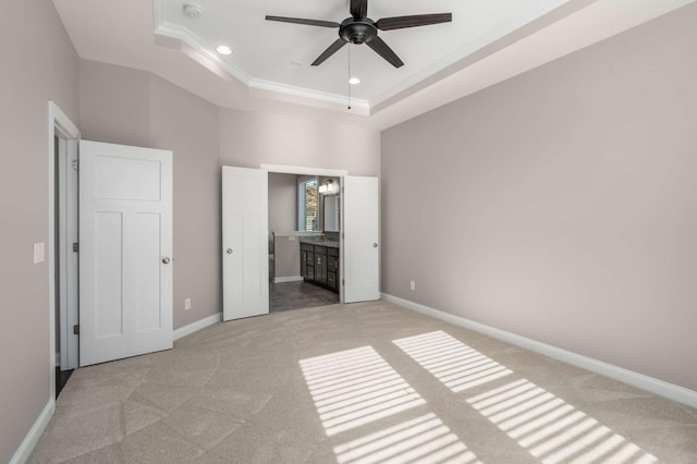 unfurnished bedroom featuring light colored carpet, baseboards, ensuite bathroom, a tray ceiling, and recessed lighting