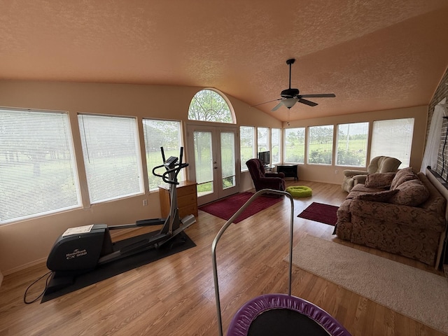 interior space with french doors, a textured ceiling, vaulted ceiling, and wood finished floors