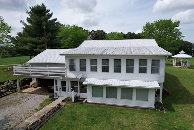 rear view of property featuring a lawn, metal roof, a gazebo, driveway, and a carport