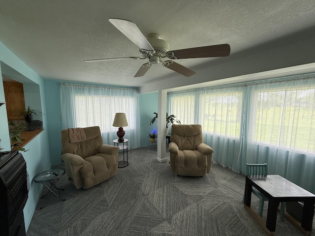 sitting room with carpet floors, ceiling fan, and a textured ceiling