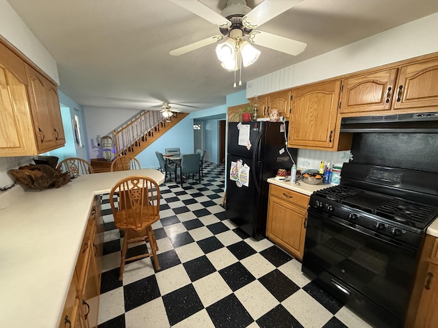 kitchen featuring ceiling fan, light countertops, black appliances, light floors, and under cabinet range hood