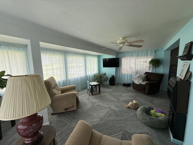 living area featuring carpet floors, a textured ceiling, and ceiling fan