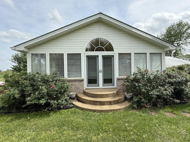 back of house with brick siding, a lawn, french doors, and a sunroom