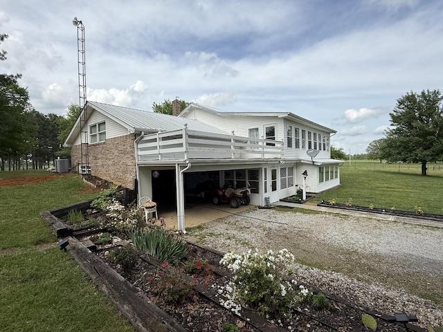 back of house featuring a sunroom, a chimney, central air condition unit, a yard, and driveway