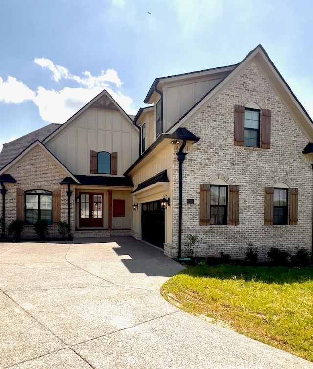 view of front of property featuring brick siding, board and batten siding, french doors, and concrete driveway