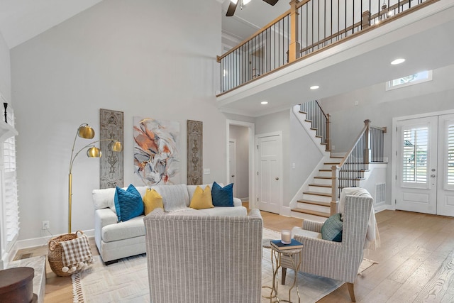 1209 Janie Sue Ct, Lebanon, TN 37087 - living room featuring a high ceiling, stairs, a ceiling fan, light wood-style flooring, and baseboards